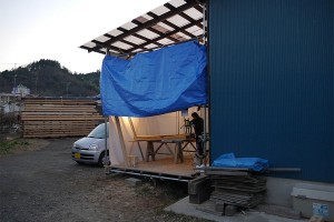一人小屋の外で大型のツールで檜を削っている棟梁